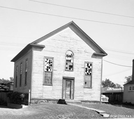 A black and white picture of a wood frame church